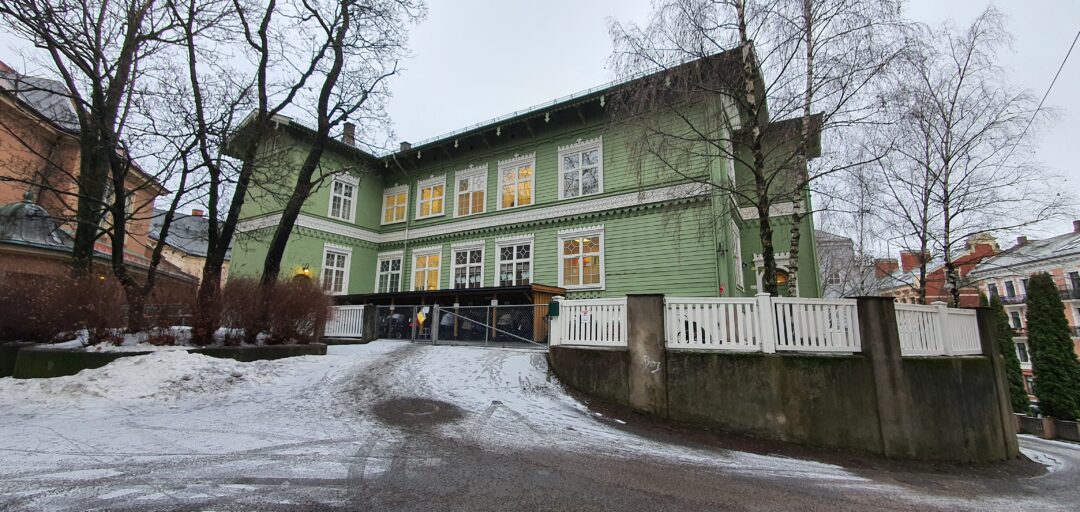 Grønn bygning med en snødekt innkjørsel