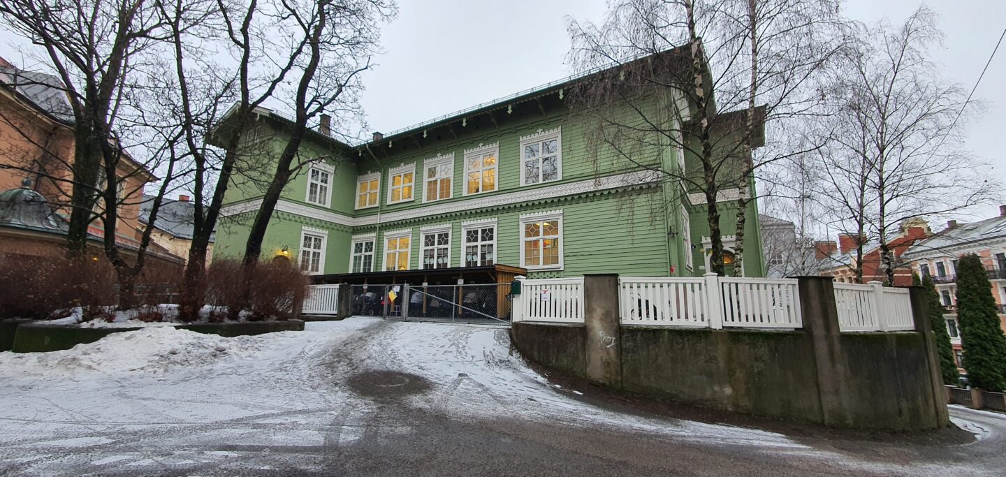 Grønn bygning med en snødekt innkjørsel